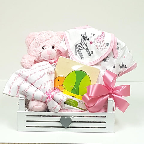 Baby's first teddy, a onesie, receiving blanket, classic wood puzzle and baby bib nestled with love in a cute wooden baby gift basket box.