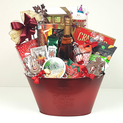 A special Christmas gift basket loaded with sweet and salty treats, cheese, sparkling cider, crackers, coffee, tea and a couple keepsake ornaments.
