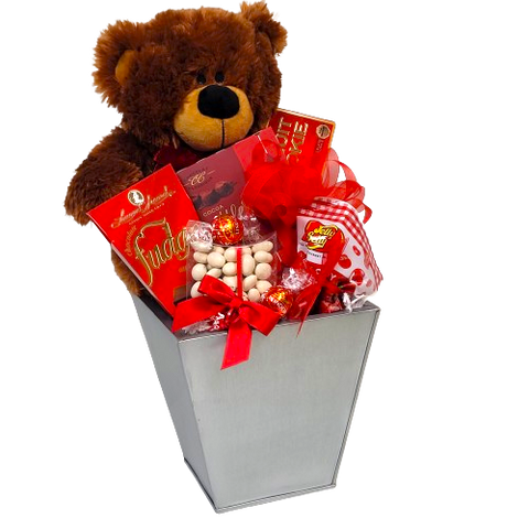 A cuddly plush bear delivers lots of snuggles and delicious treats with this gift basket. There's truffles, candies, cookies & more! It's a Beary-Licious gift basket to receive!