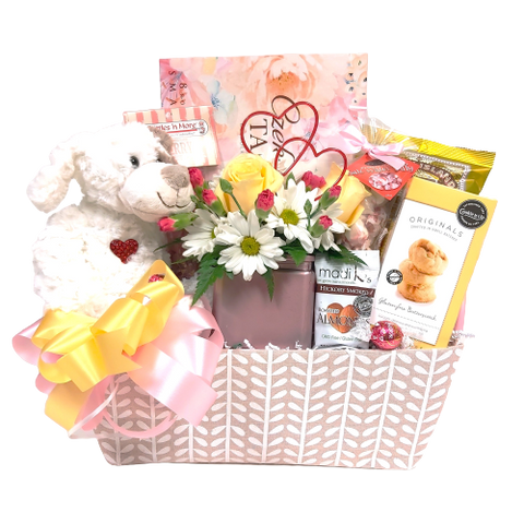 Send a loving touch with this pretty pastel basket filled with sweet treats to enjoy along with a pretty floral cube arrangement and a cute plush animal to cuddle.