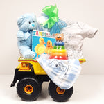 A dump truck baby gift basket filled with a baby onesie, plush blanket, baby's first teddy,a board book and a classic stacker wooden toy.
