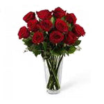 A dozen premium red roses beautifully arranged in a clear glass vase
