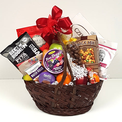 A gift basket containing a mix of fruit nestled in a generous collection of sweet and salty treats.
