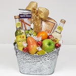 A silver fruit gift basket holding a bit of sweet, a bit of salty, some fruit and some refreshing sparkling water.