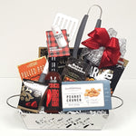 A beautiful stainless steel grill gift basket containing a set of BBQ utensils, BBQ sauce and seasonings, bar mix munchies, truffles and peanut crunch too.