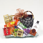 A beautiful glass tray gift basket adorned with a classic teapot and a variety of tea and biscuits to indulge in.