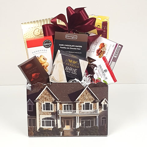 A beautiful house box gift basket filled with crackers and cheese and sweet treats to eat. 