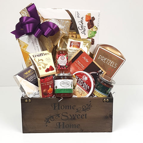 A beautiful wood housewarming gift basket crate holds chocolates, cheese, crackers, red pepper jelly, smoked salmon, cookies and lots more. 