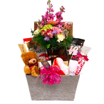 Large basket with floral arrangement nestled amongst chocolates, nuts, smoked salmon, cheese, plush bear and more.