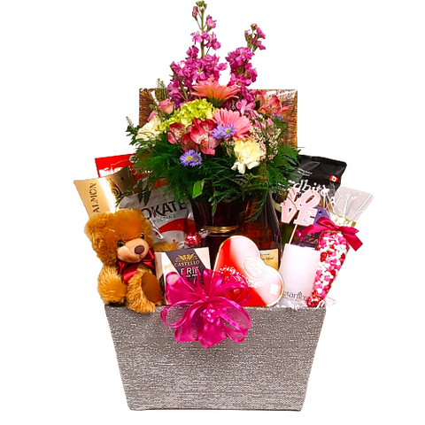 Large basket with floral arrangement nestled amongst chocolates, nuts, smoked salmon, cheese, plush bear and more.
