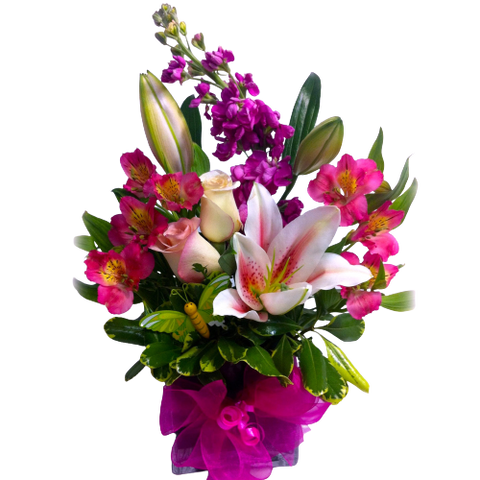 Pretty flowers nestled in a glass vase brimming with an assortment of roses, alstromeria and more with lush greens to make it complete.