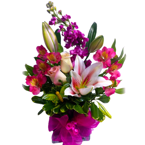 Pretty cube vase arrangement with hues of pink in roses, alstromeria, stock and lily blooms.